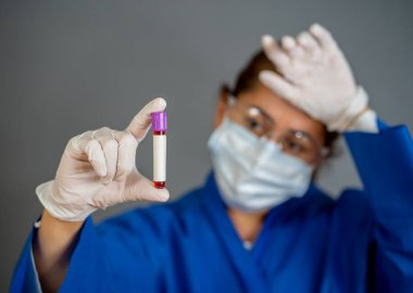 COVID-19. PPE 'deki doktor ya da laboratuvar teknisyeni. Kişisel koruyucu ekipman. Hastanedeki hastadan alınan kan örneği tüpünü tutuyor. Antikor ve aşı araştırmaları için Coronavirus kan testi.