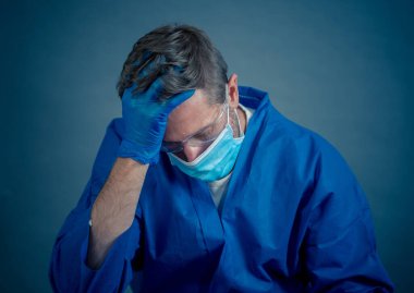 COVID-19. Koronavirüsün enfekte olduğu vakalar ve ölü sayıları artarken yorgun düşmüş doktor endişeli görünüyor. Duygusal stres, sağlık çalışanlarının desteğe, kişisel koruma ekipmanlarına ve tıbbi malzemelere ihtiyacı olması..