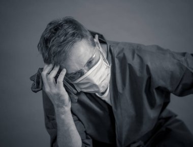 COVID-19. Koronavirüsün enfekte olduğu vakalar ve ölü sayıları artarken yorgun düşmüş doktor endişeli görünüyor. Duygusal stres, sağlık çalışanlarının desteğe, kişisel koruma ekipmanlarına ve tıbbi malzemelere ihtiyacı olması..