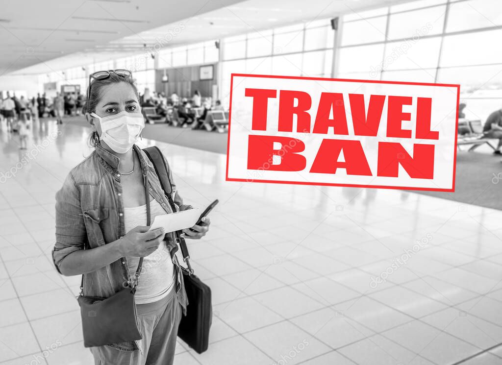 COVID-19 Outbreak. Image of Traveler woman with face mask stuck at airport due to flight cancellation for coronavirus pandemic and worldwide borders closures, with related words written on it.