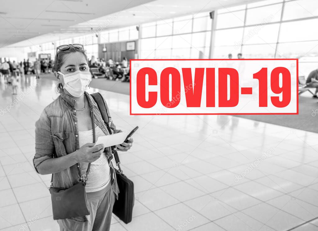 COVID-19 Outbreak. Image of Traveler woman with face mask stuck at airport due to flight cancellation for coronavirus pandemic and worldwide borders closures, with related words written on it.