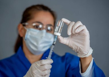 COVID-19 Coronavirus aşısı. Sars-CoV-2 virüsünü inceleyen şırıngalı bir bilim adamı aşı araştırması için klinik deneylere hazır. Kadın araştırmacı laboratuarda potansiyel aşıyı test ediyor..