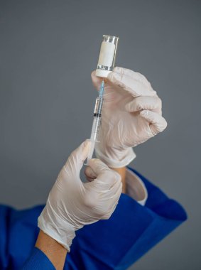 COVID-19 Coronavirus aşısı. Sars-CoV-2 virüsünü inceleyen şırıngalı bir bilim adamı aşı araştırması için klinik deneylere hazır. Kadın araştırmacı laboratuarda potansiyel aşıyı test ediyor..