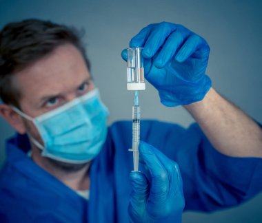 COVID-19 Coronavirus aşısı. Sars-CoV-2 virüsünü inceleyen şırıngalı bir bilim adamı aşı araştırması için klinik deneylere hazır. Erkek araştırmacı laboratuvarda potansiyel aşıyı test ediyor..