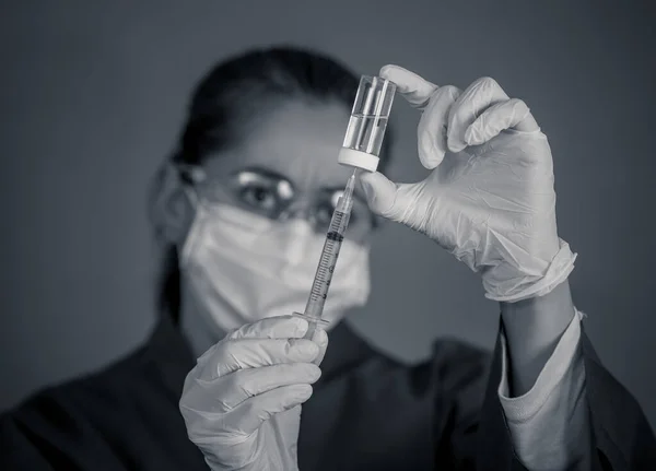 COVID-19 Coronavirus Vaccine. Doctor scientist with syringe analyzing virus Sars-CoV-2 in research for vaccine to be ready for clinical trial. Female researcher testing potential vaccine at the lab.