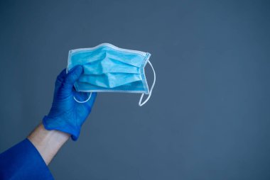 COVID-19. Doktor ya da hemşire yüz maskesi tutuyor. Virüsün yayılmasını engelleyin, kendinizi ve diğerlerini koruyun ve hasta bakımı ve sağlık görevlilerinin güvenliği için gerekli malzeme ve ekipman sağlanmasına yardım edin..