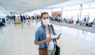 COVID-19 dünya çapında sınırlar kapanıyor. Yüzü maskeli gezgin, diğer ülkelere giriş izni verilmeyince havaalanı terminaline sıkışmış. Memleketine dönerken havaalanında mahsur kalan yolcu..