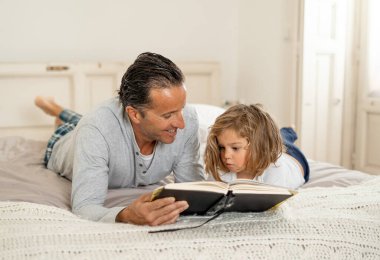 COVID-19 tecrit. Baba ve küçük kız birlikte kitap okuyorlar. Mutlu baba ve küçük kız karantinada yatakta masal okurken eğleniyorlar. Evde kal, güvende ol ve evde eğitim al..