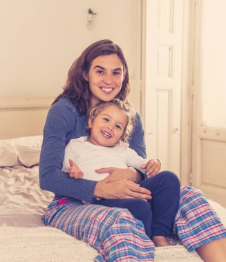 COVID-19 Karantina. Mutlu bekar anne-baba kadın ve küçük kız yalnızlık sırasında yatakta birlikte oynuyorlar. Anne ve küçük tatlı kız evde kalma kampanyası konseptinde yalnızlık çekiyor..