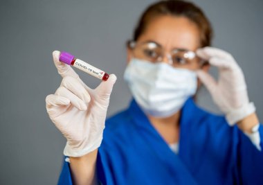COVID-19. Kişisel Koruyucu Ekipman 'daki doktor ya da laboratuvar teknisyeni elinde enfekte olmuş hastadan alınan kan örneklerini tutuyor. Aşı ve tıbbi tedavi için Coronavirus kan testi.