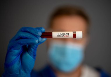 COVID-19. Kişisel Koruyucu Ekipman 'daki doktor bilim adamı laboratuvar hastanesinde enfeksiyon kapmış bir hastanın kan örneklerini tutuyor. Tıbbi tedavi ve aşı araştırmaları için Coronavirus kan testi.