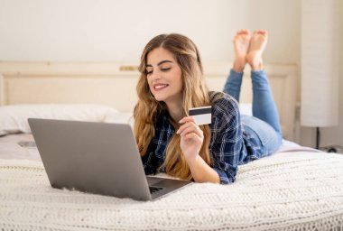 COVID-19 Salgını. Kapatma ve online alışveriş. Kredi kartıyla çekici genç bir kadın dizüstü bilgisayar kullanarak Coronavirus kilitleme ve sosyal uzaklık süresince evdeki internetten yemek alıyor..