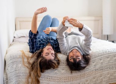 COVID-19 tecrit. Coronavirus sosyal mesafesi ve karantinası sırasında cep telefonuyla online müzik dinleyen kendinden emin ve pozitif kadın sevgililerin portresi. Evde kal, sağlıklı kal..