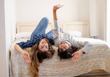 COVID-19 tecrit. Coronavirus sosyal mesafesi ve karantinası sırasında cep telefonuyla online müzik dinleyen kendinden emin ve pozitif kadın sevgililerin portresi. Evde kal, sağlıklı kal..