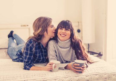 COVID-19 tecrit. Kendinden emin ve iyimser kadınlar en iyi kız arkadaşlar yatakta konuşurken ve gülerken sıcak içecekler evde yalnızken. Evde kal. Sağlığını ve güvenliğini koru..
