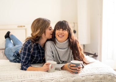 COVID-19 tecrit. Kendinden emin ve iyimser kadınlar en iyi kız arkadaşlar yatakta konuşurken ve gülerken sıcak içecekler evde yalnızken. Evde kal. Sağlığını ve güvenliğini koru..
