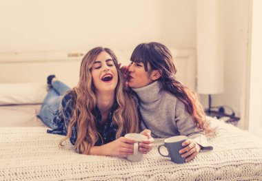 COVID-19 tecrit. Kendinden emin ve iyimser kadınlar en iyi kız arkadaşlar yatakta konuşurken ve gülerken sıcak içecekler evde yalnızken. Evde kal. Sağlığını ve güvenliğini koru..