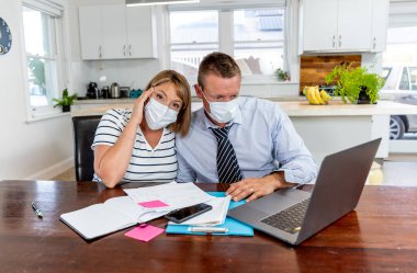 Coronavirus ekonomik durgunluğu. Karantina süresince ev ekonomisi ve küçük işletme borçları yüzünden kendilerini izole eden maskeli stresli bir çift. COVID-19 pandemik Küresel Ekonomik Krizin Etkisi.