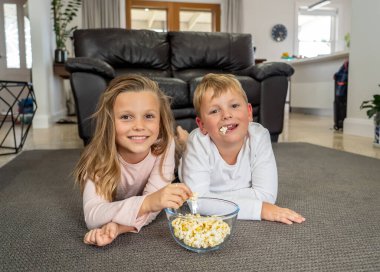 COVID-19 salgını, tecrit. Evde kal, hayat kurtar. Kafkasyalı çocukla kız tecritte mutlu bir şekilde karantina sırasında televizyon izleyerek eğleniyorlar. Koronavirüsün yayılmasını engellemek için..