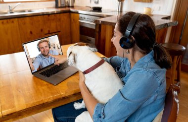COVID-19 evde kal. Kendine dikkat et. Evcil köpek videosu olan mutlu kadın laptopunu kullanarak arkadaşını arıyor. Kocasıyla internette sohbet eden eş, Coronavirus sınırlarının kapanması nedeniyle başka bir ülkede mahsur kalmış..