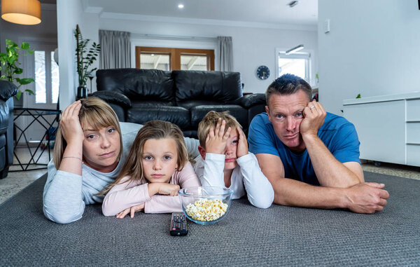 Coronavirus lockdow. Bored family watching tv helpless in isolation at home during quarantine COVID 19 Outbreak. Mandatory lockdowns and self isolation recommendations forces families stay home.