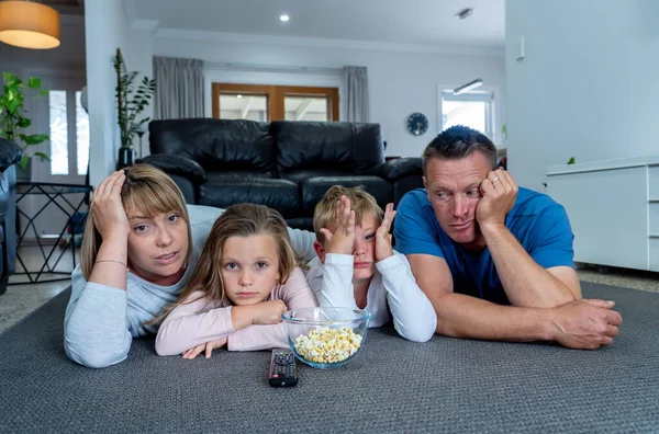 Coronavirus lockdow. Bored family watching tv helpless in isolation at home during quarantine COVID 19 Outbreak. Mandatory lockdowns and self isolation recommendations forces families stay home.