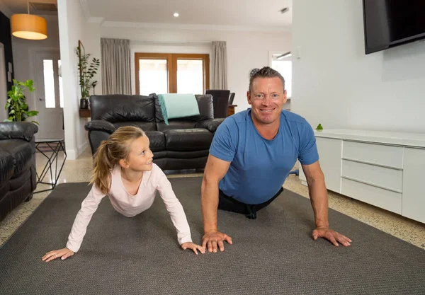 COVID-19 shutdown. Happy father and daughter exercising together during quarantine. Family having fun doing indoors physical activity. Stay home, Exercise, Health Self-care for Coronavirus isolation.