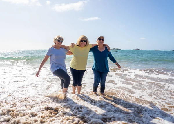 一群可爱的六十多岁的老朋友们散步 在海上洒水 玩得很开心 三个成熟健康的退休女性笑着享受退休生活和户外运动 — 图库照片
