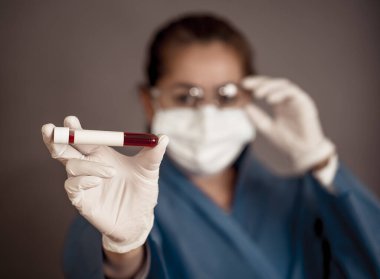 COVID-19. PPE 'deki doktor ya da laboratuvar teknisyeni. Kişisel koruyucu ekipman. Hastanedeki hastadan alınan kan örneği tüpünü tutuyor. Antikor ve aşı araştırmaları için Coronavirus kan testi.