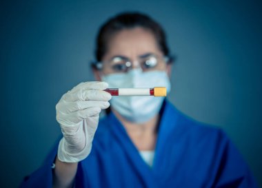 COVID-19. PPE 'deki doktor ya da laboratuvar teknisyeni. Kişisel koruyucu ekipman. Hastanedeki hastadan alınan kan örneği tüpünü tutuyor. Antikor ve aşı araştırmaları için Coronavirus kan testi.