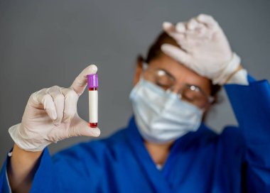 COVID-19. PPE 'deki doktor ya da laboratuvar teknisyeni. Kişisel koruyucu ekipman. Hastanedeki hastadan alınan kan örneği tüpünü tutuyor. Antikor ve aşı araştırmaları için Coronavirus kan testi.