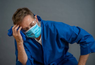 COVID-19. Koronavirüsün enfekte olduğu vakalar ve ölü sayıları artarken yorgun düşmüş doktor endişeli görünüyor. Duygusal stres, sağlık çalışanlarının desteğe, kişisel koruma ekipmanlarına ve tıbbi malzemelere ihtiyacı olması..
