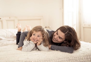 COVID-19 Karantina. Mutlu bekar anne-baba kadın ve küçük kız yalnızlık sırasında yatakta birlikte oynuyorlar. Anne ve küçük tatlı kız evde kalma kampanyası konseptinde yalnızlık çekiyor..
