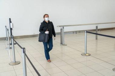 COVID-19 pandemik kısıtlamalar. Hükümetler Coronavirus 'un yayılmasını engellemek için seyahatleri kısıtladığından yabancı bir ülkede sıkışıp kaldıktan sonra, havaalanında eve dönmek için bekleyen genç kadın..