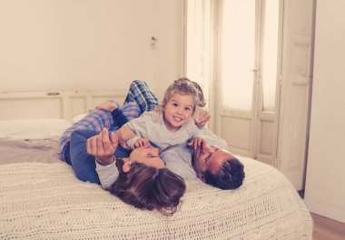 COVID-19 tecrit. Güzel, mutlu bir aile rahatlıyor ve yatakta birlikte oynuyorlar. Kendini izole ederken evde kalıyorlar. Anne, baba ve 