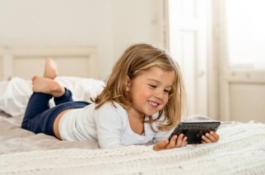 COVID-19 tecrit. Evde kal, bağlantıda kal ve e-öğrenim yap. Coronavirus karantinası sırasında cep telefonundan arayan ve ailesiyle görüntülü konuşma yapan küçük bir kız. İnternette öğretmenle telefonda konuşan bir çocuk..