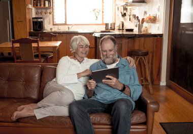 Dijital tablet kullanarak ailesini arayan mutlu yaşlı adam ve kadın videoları. Çift birlikte televizyon izlemekten ya da internette haber izlemekten keyif alıyor. Coronavirus ve evdeki hayat.