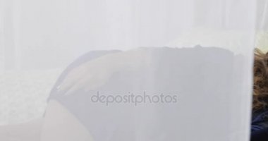 Genç bir kadın günün ortasında evde rahat bir yatakta uyuyor. Dolly vurdu..