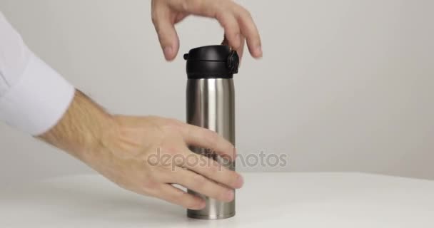 灰色の背景に魔法瓶を開く男の手 — ストック動画