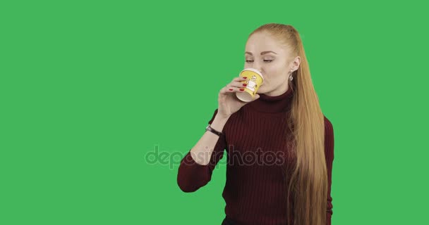 白种女性模型在冬天外套喝茶在绿色背景 — 图库视频影像