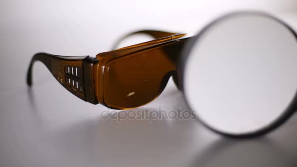 レーザー保護メガネはテーブルの上です 緑色のレーザー安全メガネのクローズ アップ レーザー照射による損傷します — ストック動画