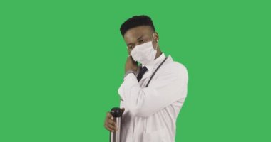 phonendoscope ile tıbbi üniformalı genç Afro-Amerikan doktor beyaz maske ve içecekler kahve termo kupa kaldırır.