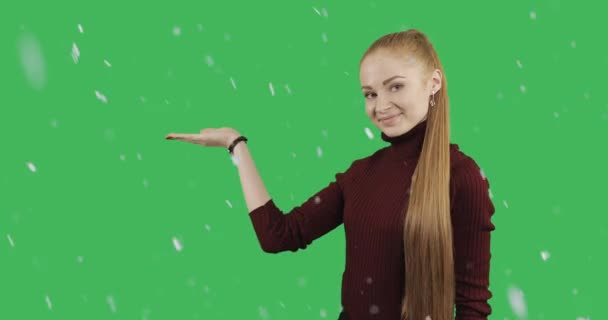 长红头发的漂亮女人显示她的手在下雪的天气在绿色色度关键背景下销售的象征 — 图库视频影像