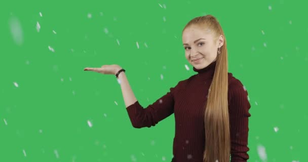 赤くて長い髪のきれいな女性 手緑クロマ キー背景に雪での割引のシンボルを表示します — ストック動画