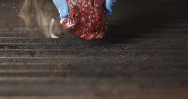 Кухарська рука в рукавичці кладе шматочок свіжого м'яса на електричний гриль . — стокове відео