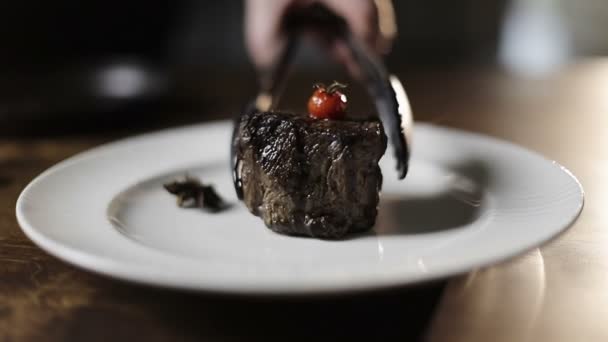 Aşçının eli beyaz tabağa taze bir biftek koyar ve tabağın son süslemesini yapar.. — Stok video