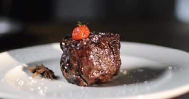 Aşçının eli beyaz tabağa taze bir biftek koyar ve tabağın son süslemesini yapar..