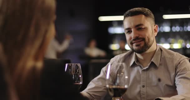 Liebespaar klirrt im Café mit Gläsern und trinkt Rotwein. — Stockvideo