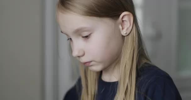 Menina bonito coloca uma máscara protetora médica. A criança se senta em casa em isolamento . — Vídeo de Stock