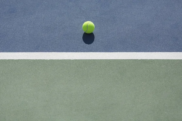 Mavi ve yeşil sabit beyaz çizgiyle bölünmüş kortunda tenis topu — Stok fotoğraf